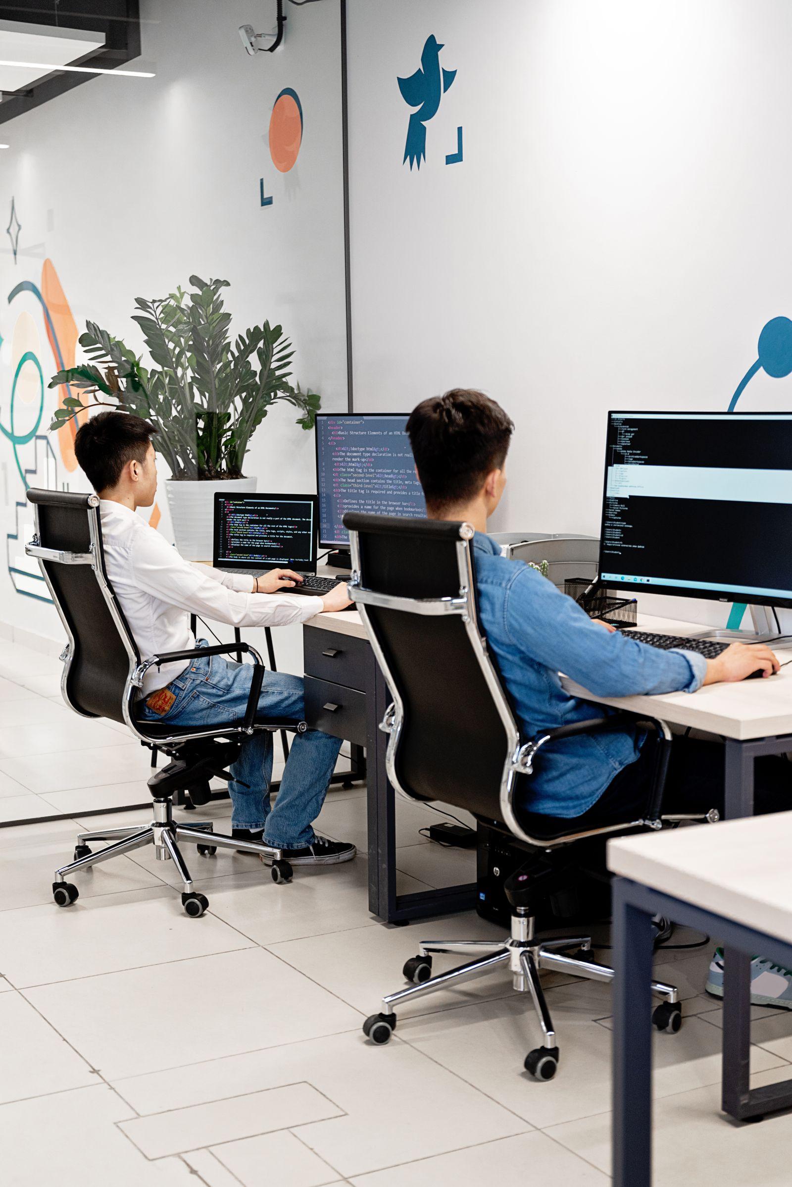 Two linguists collaborating on a translation review at their monitors